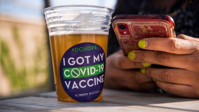 美国华盛顿某疫苗接种中

心外一位接种完毕的女士在享用免费派发的啤酒（6/5/2021）